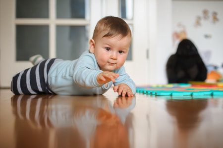 Cute baby boy crawls on the home floor, explore the world and learn to move. Love and family emotionの写真素材
