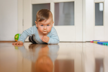 Cute baby boy crawls on the home floor, explore the world and learn to move. Love and family emotionの写真素材