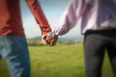 A couple is holding hands in the autumn or spring day in the park. Close-up of loving couple holding hands while walking. Selective focusの写真素材