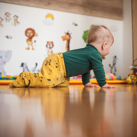 Cute baby boy crawls on the home floor, explore the world and things around him. Love and family emotionの写真素材