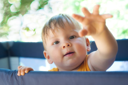 Portrait of a cute toddler boy playing in the playpen. Concept of love, care, parenthoodの写真素材