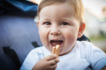 Portrait of happy and smilling cute baby boy eating his favorite child biscuit. Healthy nutrition for kids conceptの写真素材