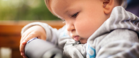 Cute baby boy is deeply engrossed in examining an object with curiosity and concentration, embodying the wonder of early childhoodの写真素材