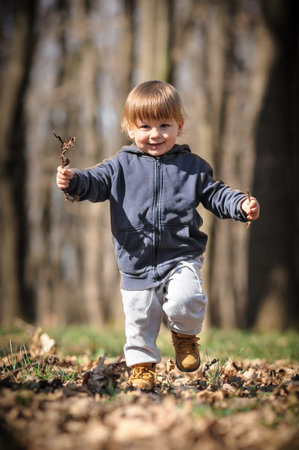 Toddlers autumn adventure. Curious kid crouches among fallen leaves, discovering the wonders of...