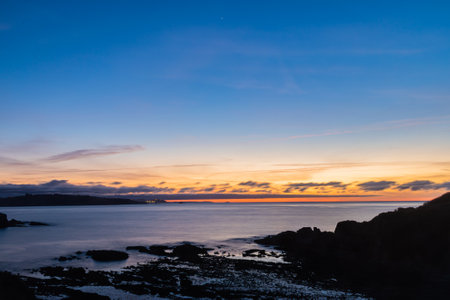 In the photograph you can see a sunset in the blue hour with long exposure with the cliffs in front.の写真素材