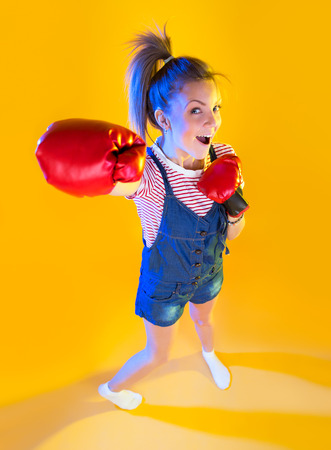 Funny fitness woman with boxing gloves, isolated on yellowの写真素材
