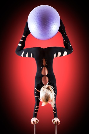 circus actor standing on the hand on a red backgroundの写真素材