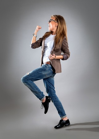 Celebrating cheering businesswoman isolated. Funny image of happy young business woman in full length. High angle view with near fisheye effect. isolated on gray background.の写真素材
