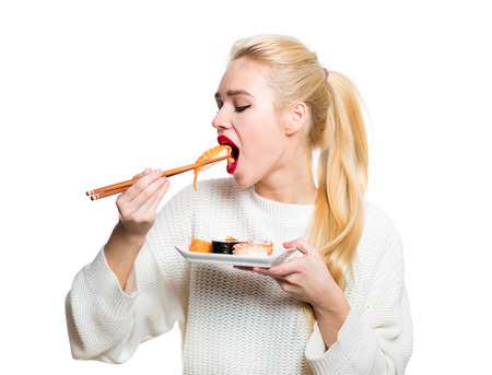 Whitehaired girl eating sushi with a chopsticks isolatedの写真素材