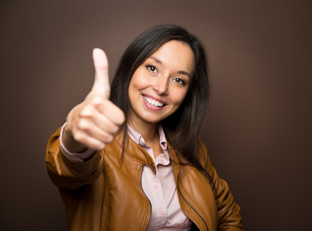 Woman giving thumbs up approval hand sign gesture smiling happy isolated on white background の写真素材