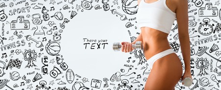 Torso of a young fit woman lifting dumbbells on white and draw backgroundの写真素材