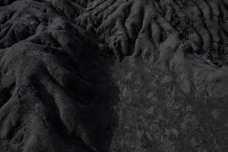 Dark sand, with irregular formations, due to time and nature.