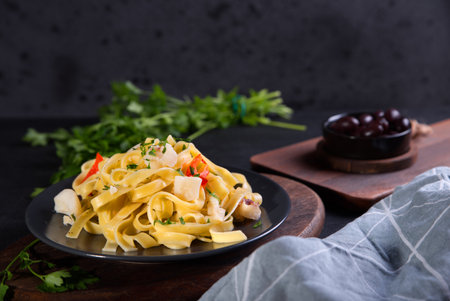 Pasta with pieces of cuttlefish, parsley, olives and peppers.の写真素材