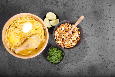 Typical Peruvian dish known as chicken soup, in a wooden bowl with lemon and chives.の写真素材