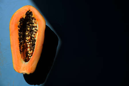 Papaya on a blue background, lit from the left with a large shadow on the right.の写真素材