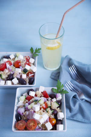 Greek salad in square plates and lemonade on a light blue background.の写真素材