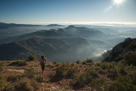 Woman running on a trail in the mountains with fog in the background