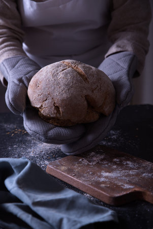Hands putting freshly made bread on the table.