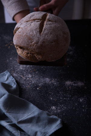 Hands putting freshly made bread on the table.の写真素材