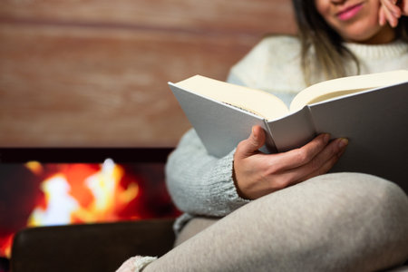 Close-up of woman reading a book in the warmth of her home.の写真素材