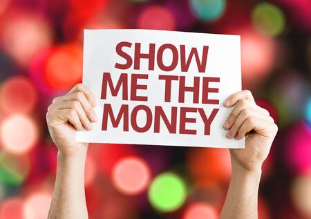 Hands holding Show Me The Money card with colorful background with defocused lightsの写真素材