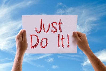 Hands holding Just Do It card with sky backgroundの写真素材
