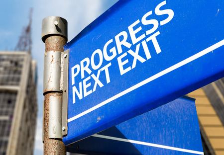 Progress Next Exit written on the road sign with city backgroundの写真素材