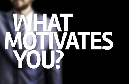 Business man in black background with the text: What motivates you?の写真素材