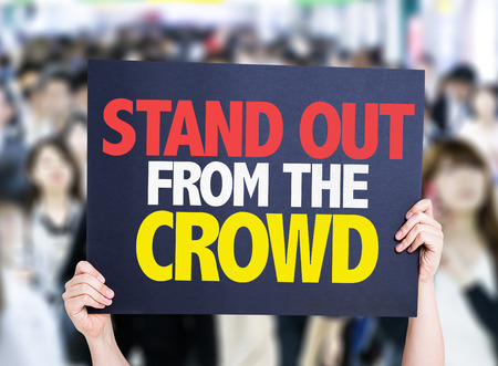 Hands holding cardboard on crowd background with text: Stand out from the crowdの写真素材