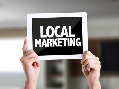 Hands holding tablet pc on a house background with text: Local marketingの写真素材