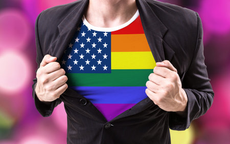 Businessman stretching suit with USA LGBT flag on bokeh background