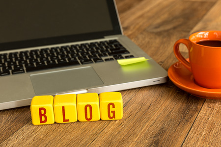 Blog written on a wooden cube in front of a laptopの写真素材
