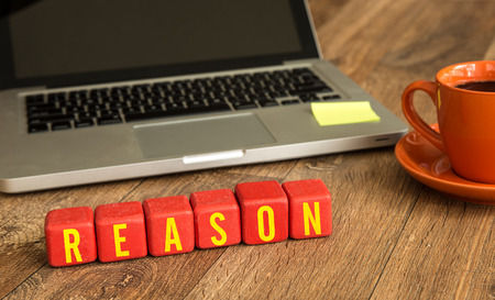 Reason written on a wooden cube in front of a laptopの写真素材