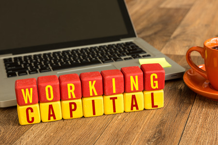 Working Capital written on a wooden cube in front of a laptopの写真素材
