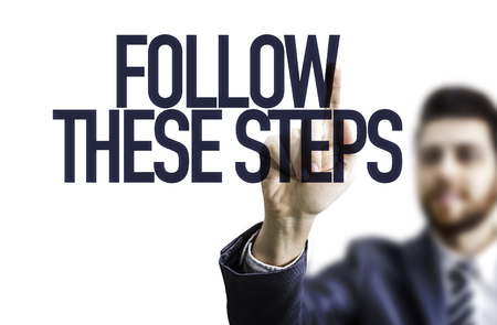 Business man pointing the text: Follow These Stepsの写真素材