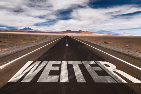 Continue in German written on desert roadの写真素材
