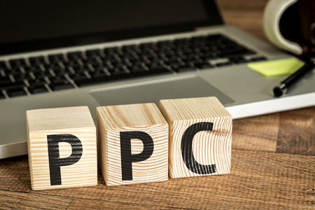 PPC Pay Per Click written on a wooden cube in front of a laptopの写真素材
