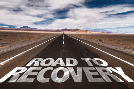 Road to recovery written on the road sign with clouds and sky backgroundの写真素材