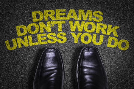 Text on road with business shoes background: Dreams don't work unless you doの写真素材