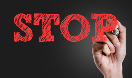 Hand holding a marker with Stop concept
