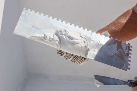 Builder using plastering tool for finishing wallの写真素材