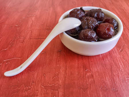 Delicious sweet gooseberry with syrup on white bowl. Red backgroundの写真素材