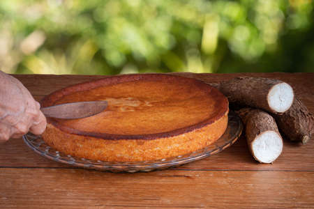 Hand cutting manioc cake on green background. Copy space.の写真素材