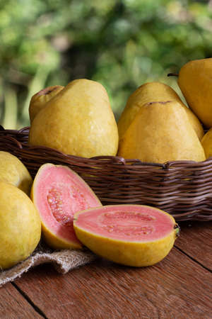 Photo of guava fruit cut in basket on wooden background and blurred garden backgroundの写真素材