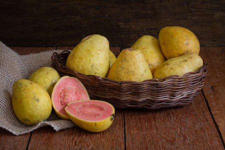 Photo of guava fruit cut in basket on wooden background.の写真素材
