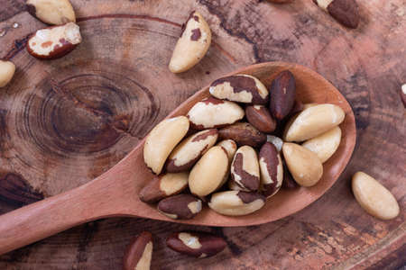Brazilian nut, known as "Castanha do ParÃ¡" in wooden spoon on rustic wooden background. Top viewの写真素材