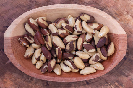 Brazilian nut, known as Castanha do ParÃ¡ in wooden bowl on wooden table. Top view