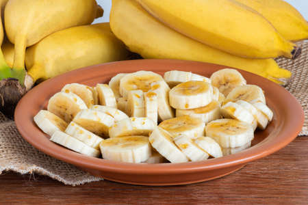 Organic bunch of ripe yellow bananas. Pieces cut into plate with honey.Copy spaceの写真素材