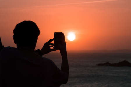 Man taking photo of sunset. Silhouetteの写真素材