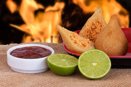 Coxinha. Traditional fried brazilian food with chicken. Background with defocused fireの写真素材